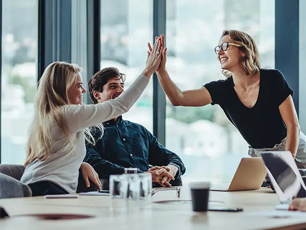 Fröhliches High-Five unter Kolleginnen während eines Meetings